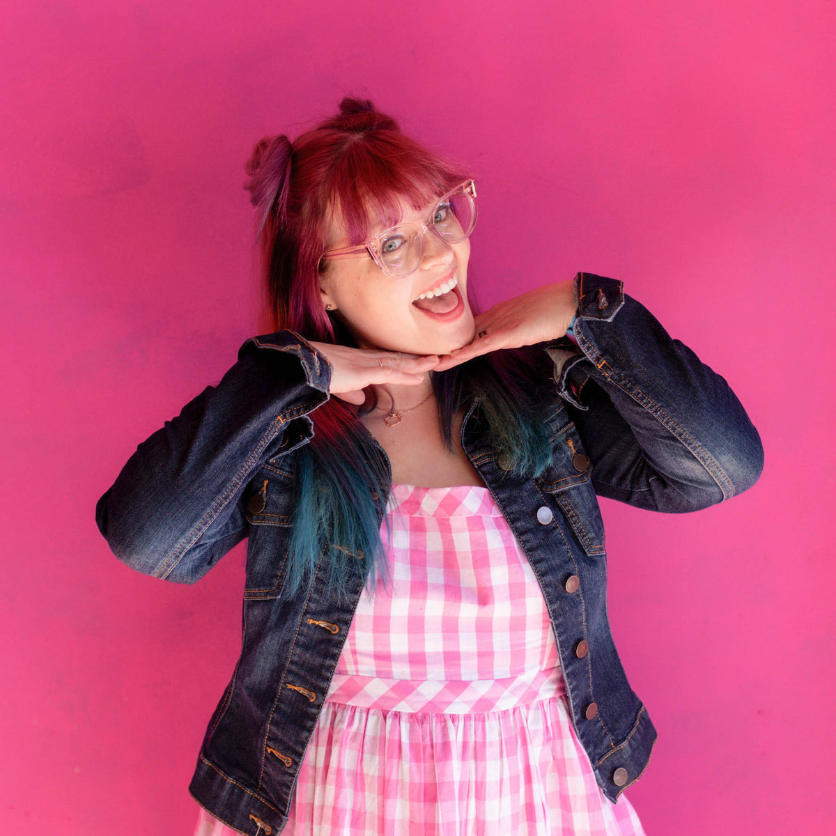 Holly wearing a denim jacket and pink checkered dress against a pink background